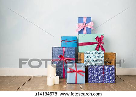 Stock Photo - Candles and stack of wrapped christmas gifts on wooden floor. Fotosearch