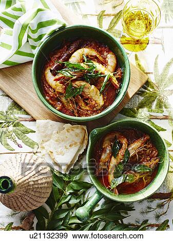 Stock Photo - Casserole of prawns and garnish with glass of Indian coconut vinegar. Fotosearch