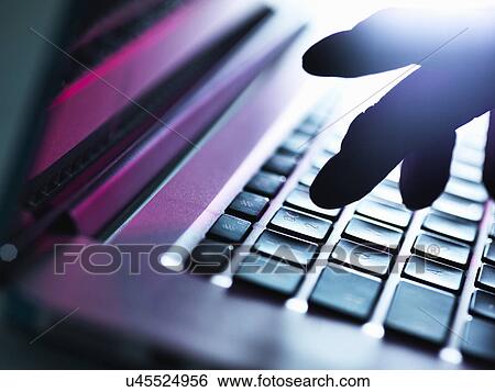 Close up of silhouetted male hand typing on laptop keyboard View Large Photo Image Stock Photograph - Close up of silhouetted male hand typing on laptop keyboard. Fotosearch