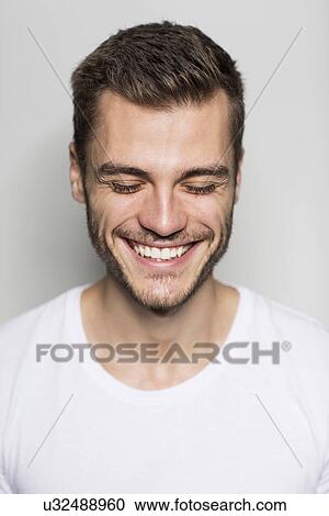 Stock Image - Close up portrait of smiling young man with eyes closed. Fotosearch