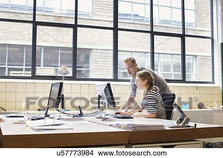Picture - Colleagues having informal meeting at office desk. Fotosearch