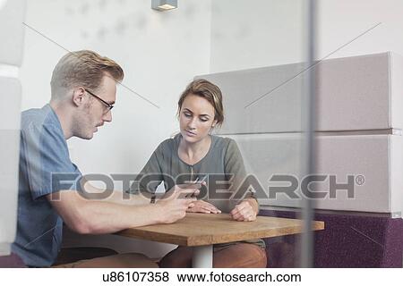 Stock Photo - Colleagues looking at digital tablet in meeting. Fotosearch