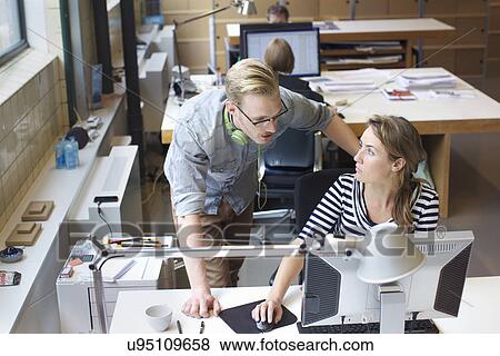 Stock Photo - Colleagues sharing informal meeting at office desk. Fotosearch