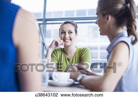 Stock Image - Colleagues talking in meeting room. Fotosearch