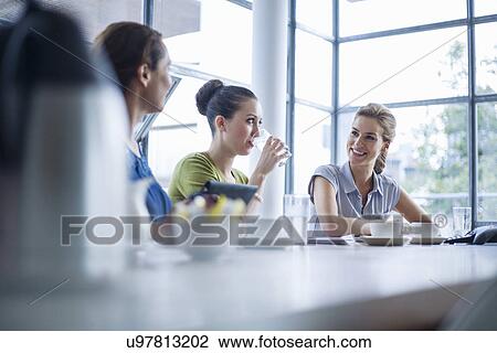 Stock Image - Colleagues talking in meeting room. Fotosearch