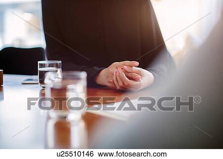 Stock Photograph - Cropped close up of mature businesswoman interviewing candidate at boardroom table. Fotosearch