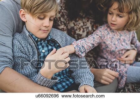 Stock Photograph - Cropped shot of young couple with son and daughter sitting on laps. Fotosearch