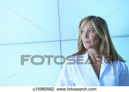 Stock Image - Doctor posing against backlit wall panel. Fotosearch