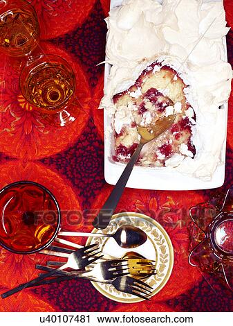 Stock Image - Drinking glasses and dish of Queen of Puddings on retro carpet. Fotosearch