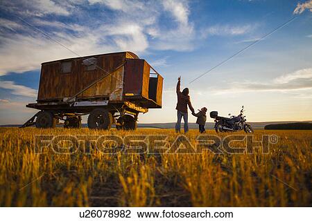 Stock Image - "Father and son looking up from autumn field at sunset, Sarsy Village, Sverdlovsk Oblast, Russia". Fotosearch