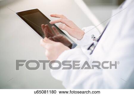 Stock Image - "female doctor using digital tablet, focus on hands". Fotosearch