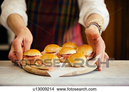 Female hands holding chopping board with prosciutto paninis View Large Photo Image Picture - Female hands holding chopping board with prosciutto paninis. Fotosearch