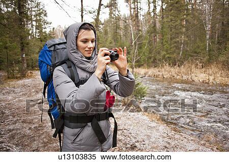 Stock Photography - "Female hiker photographing river on digital camera, Sarsy Village, Sverdlovsk Oblast, Russia". Fotosearch