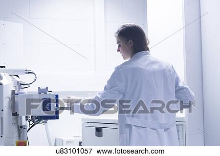 Stock Photo - Female scientist in lab using scanning electron microscope. Fotosearch