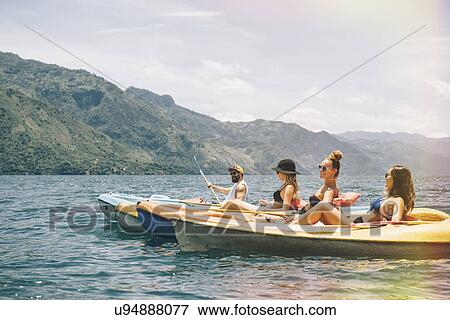 Stock Photo - "Four young adult friends kayaking on Lake Atitlan, Guatemala". Fotosearch