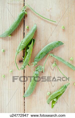 Stock Photo - Freshly picked pea pods on wooden table. Fotosearch
