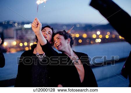 "Friends holding sparklers in air, at party" View Large Photo Image Stock Photo - "Friends holding sparklers in air, at party". Fotosearch