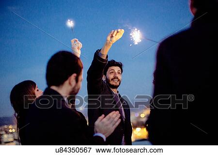 "Friends holding sparklers in air, at party" View Large Photo Image Stock Photo - "Friends holding sparklers in air, at party". Fotosearch