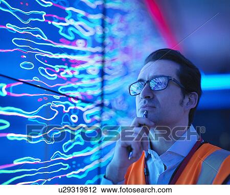 Stock Image - "Geologist studying graphical display of oil and gas bearing rock on screens, close up". Fotosearch