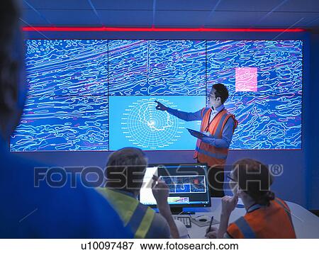 Stock Photo - Geologists studying graphical display of oil and gas bearing rock on screens. Fotosearch