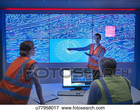 Stock Photo - Geologists studying graphical display of oil and gas bearing rock on screens. Fotosearch