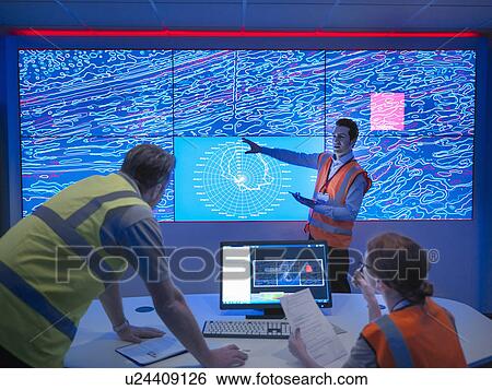Stock Photograph - Geologists studying graphical display of oil and gas bearing rock on screens. Fotosearch