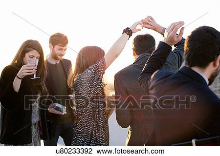 Stock Image - Group of friends drinking and dancing at party. Fotosearch