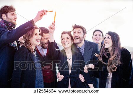Picture - Group of friends holding mini fireworks at outdoor party. Fotosearch
