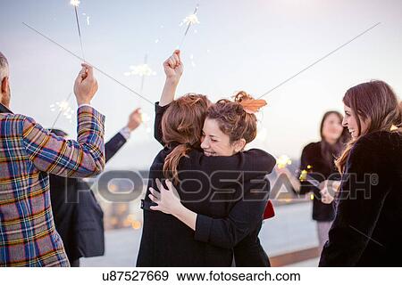 "Group of friends holding sparklers in air, at party" View Large Photo Image Stock Photo - "Group of friends holding sparklers in air, at party". Fotosearch