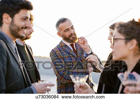 Picture - Group of friends laughing and drinking at party. Fotosearch