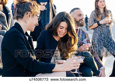 Group of friends laughing and drinking at party View Large Photo Image Stock Image - Group of friends laughing and drinking at party. Fotosearch