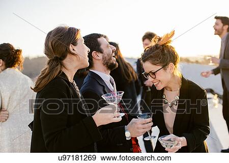 Stock Photo - Group of friends laughing and drinking at party. Fotosearch