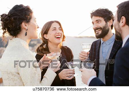 Stock Photograph - Group of friends laughing and drinking at party. Fotosearch