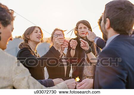 Group of friends lighting sparklers at party View Large Photo Image Stock Image - Group of friends lighting sparklers at party. Fotosearch