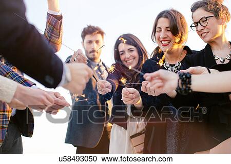 Group of friends using sparklers at party View Large Photo Image Stock Image - Group of friends using sparklers at party. Fotosearch