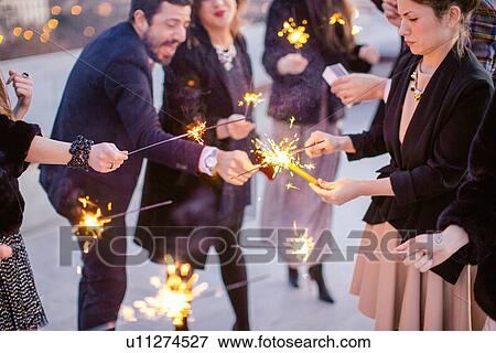 "Group of friends waving sparklers, at party" View Large Photo Image Stock Photo - "Group of friends waving sparklers, at party". Fotosearch