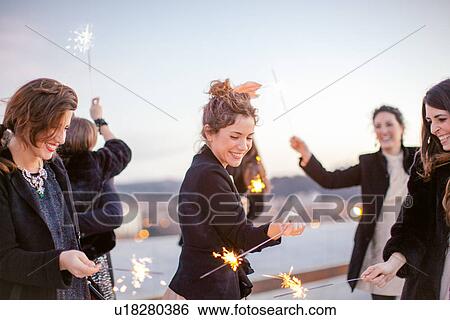 "Group of friends waving sparklers around, at party" View Large Photo Image Stock Photograph - "Group of friends waving sparklers around, at party". Fotosearch