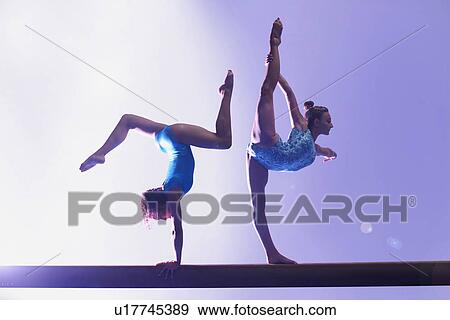 Stock Photo - Gymnasts doing routine on bar. Fotosearch