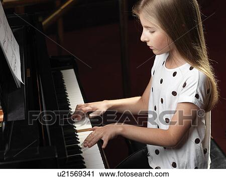 Stock Image - High angle view of girl playing piano. Fotosearch
