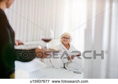 Hotel waitress serving red wine to mature businesswoman in hotel room View Large Photo Image Stock Photo - Hotel waitress serving red wine to mature businesswoman in hotel room. Fotosearch