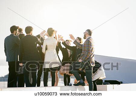 Stock Image - Large group of people making a toast at party. Fotosearch