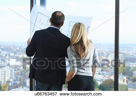 Stock Photo - "Male and female architects in front of office window with Brussels cityscape, Belgium". Fotosearch