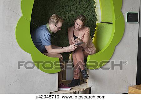 Male and female designers working on digital tablet in tree shaped office space View Large Photo Image Stock Image - Male and female designers working on digital tablet in tree shaped office space. Fotosearch
