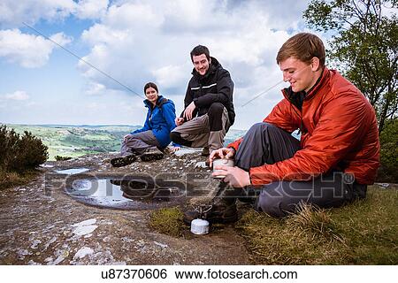 Stock Photograph - "Male and female hikers preparing camping stove on Guise Cliff, Pateley Bridge, Nidderdale, Yorkshire Dales". Fotosearch