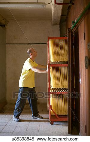 Stock Photography - "Male artisan pushing trolley of fresh spaghetti, Tuscany, Italy". Fotosearch