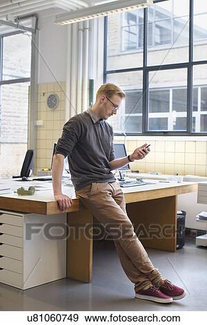 Male designers looking smartphone in creative office View Large Photo Image Stock Photo - Male designers looking smartphone in creative office. Fotosearch