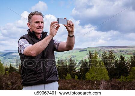 "Male hiker photographing with smartphone on heather moors, Pateley Bridge, Nidderdale, Yorkshire Dales" View Large Photo Image Stock Image - "Male hiker photographing with smartphone on heather moors, Pateley Bridge, Nidderdale, Yorkshire Dales". Fotosearch