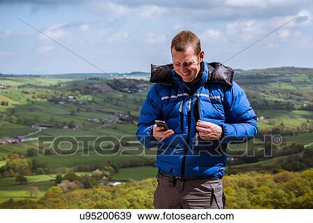 "Male hiker reading smartphone texts, Pateley Bridge, Nidderdale, Yorkshire Dales" View Large Photo Image Stock Photo - "Male hiker reading smartphone texts, Pateley Bridge, Nidderdale, Yorkshire Dales". Fotosearch