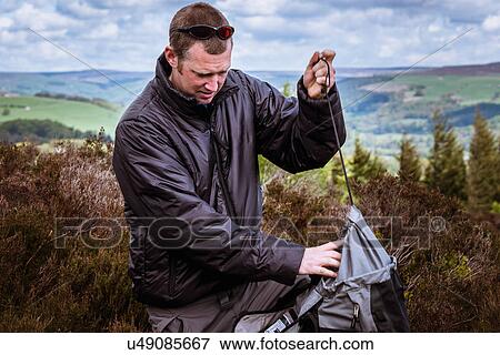 "Male hiker tying rucksack on heather moors, Pateley Bridge, Nidderdale, Yorkshire Dales" View Large Photo Image Stock Photo - "Male hiker tying rucksack on heather moors, Pateley Bridge, Nidderdale, Yorkshire Dales". Fotosearch