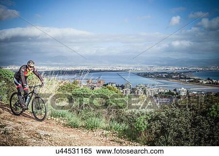 Stock Photography - "Male mountain biker speeding downhill on coastal path, Cagliari, Sardinia, Italy". Fotosearch